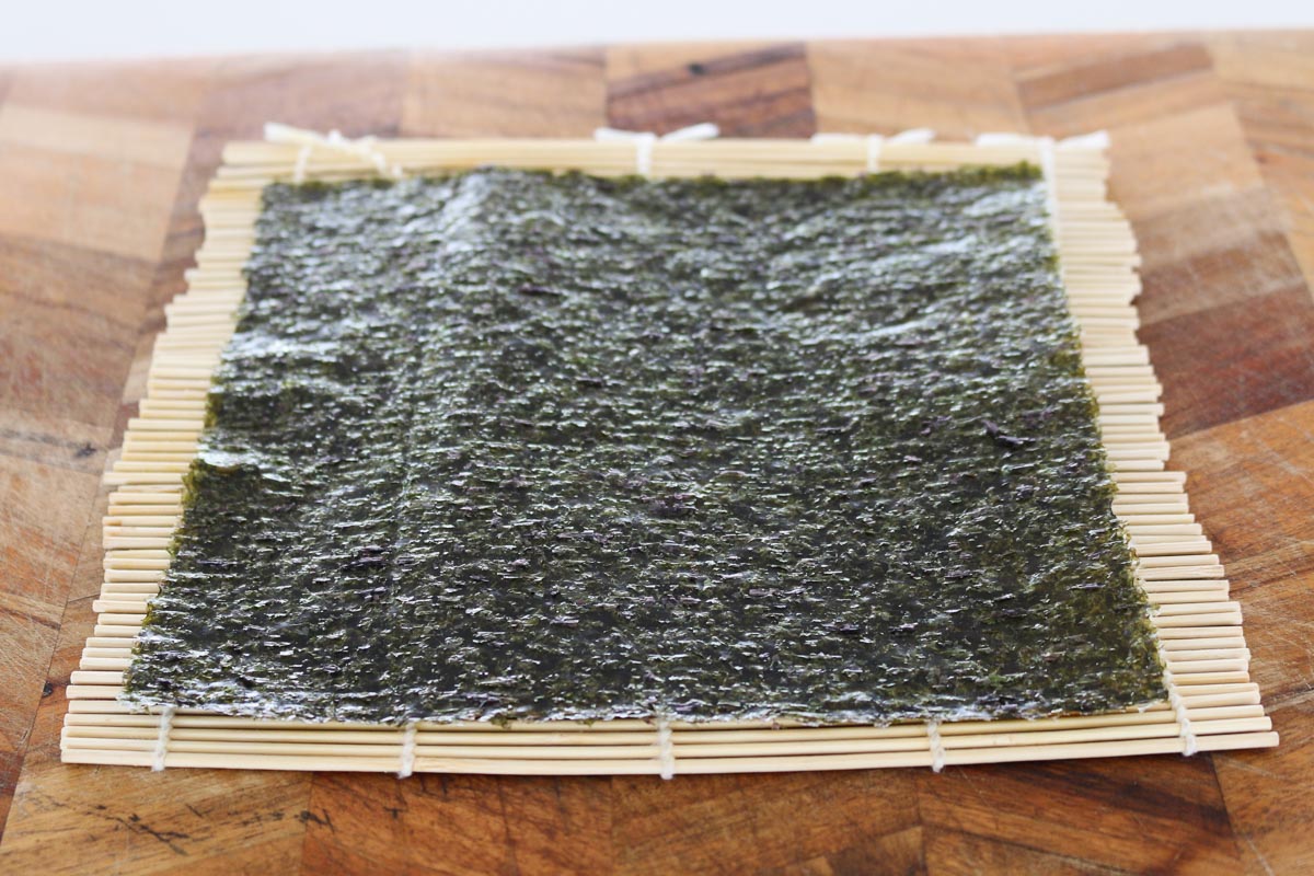 Una hoja de nori sobre una estera de bambú.