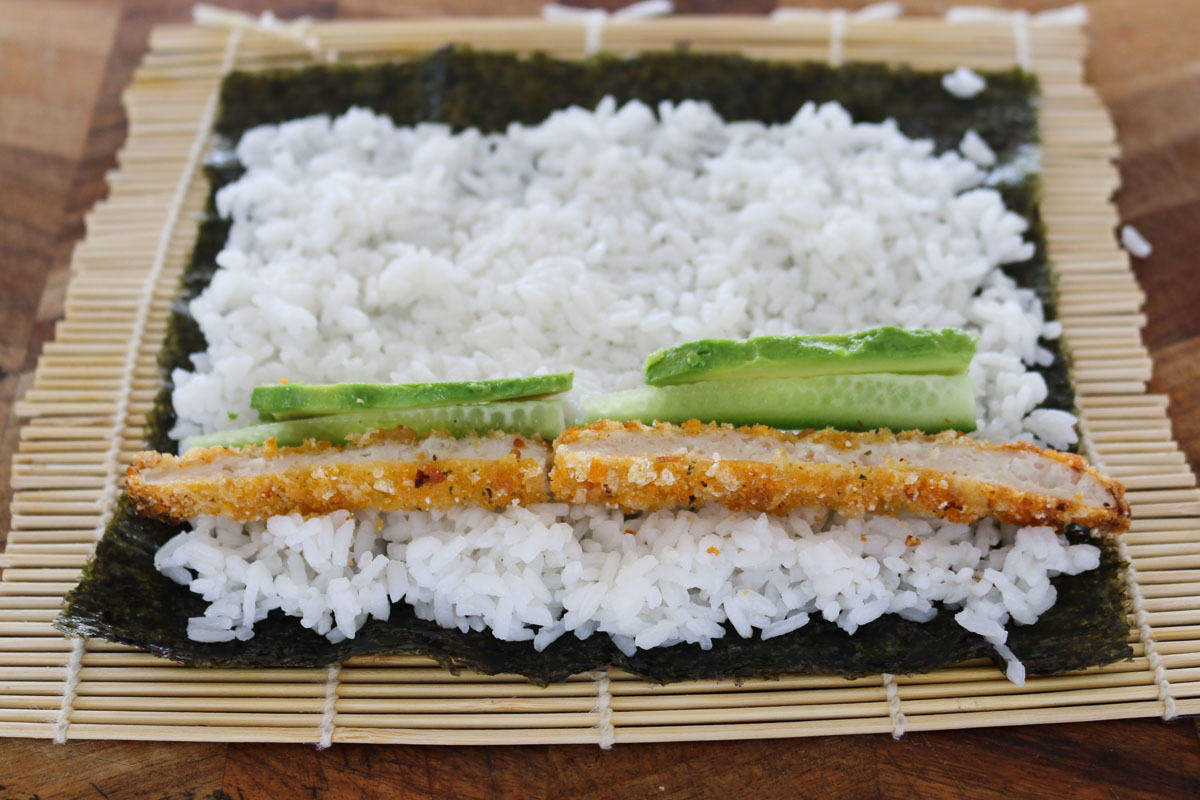 Pollo, pepino y aguacate sobre arroz de sushi en una hoja de nori.