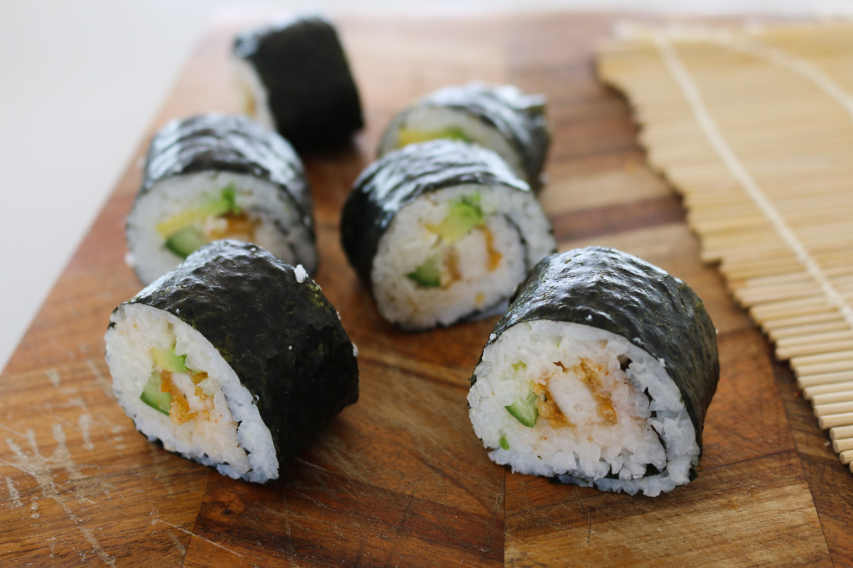 Trozos de sushi casero se cortan en una tabla de cortar.