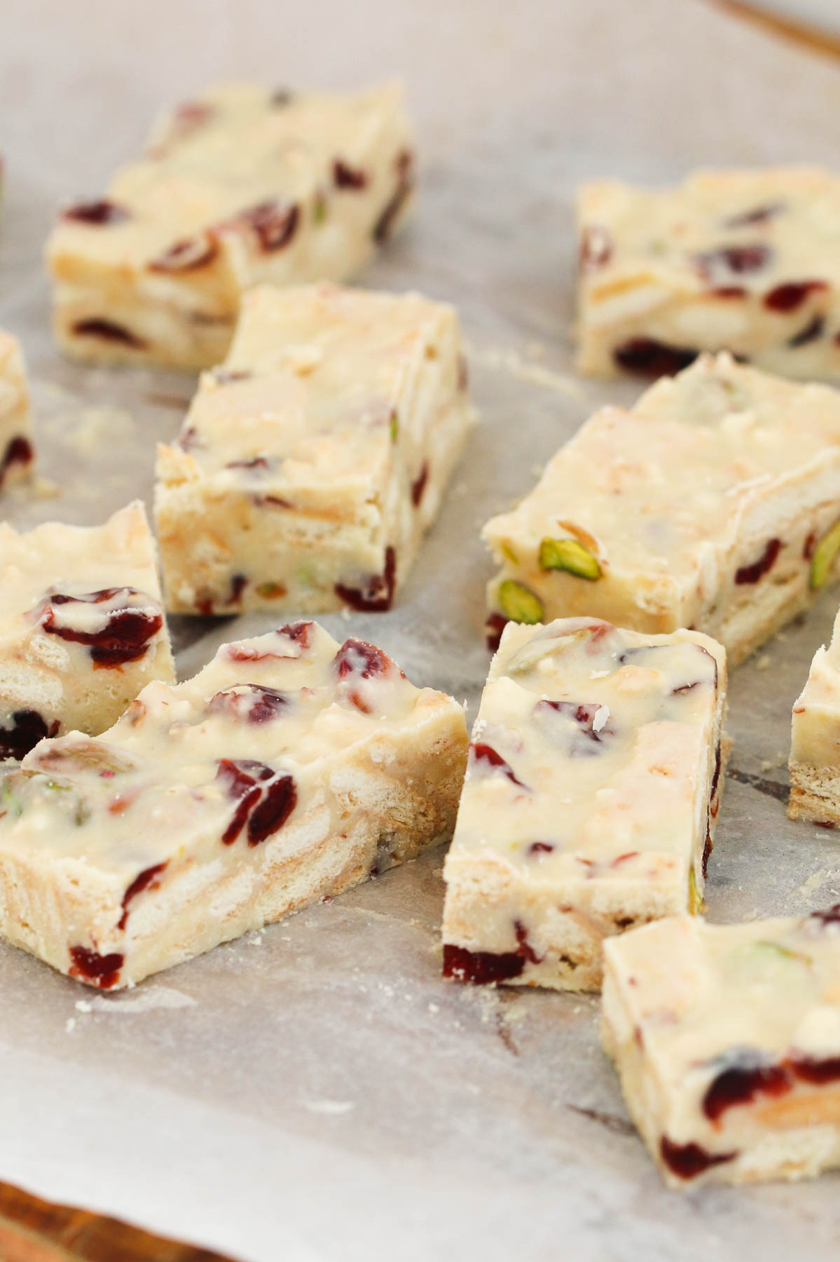 Trozos de chocolate blanco, pistacho y rodaja de arándano sobre papel de horno.